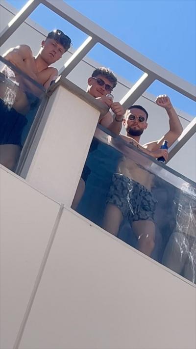Three topless men on a balcony 