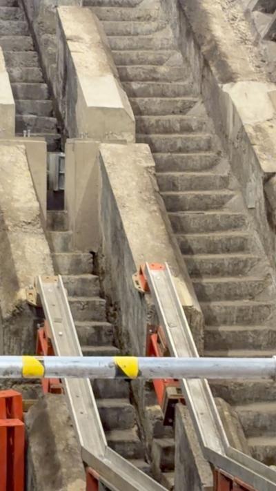 Concrete stairs can be seen beneath escalators at a Tube station.