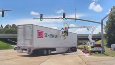 Man dangling from harness at traffic junction, he is high in the air