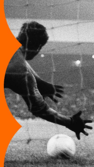Black and white photo of a goalkeeper jumping to stop the ball during a penalty.
