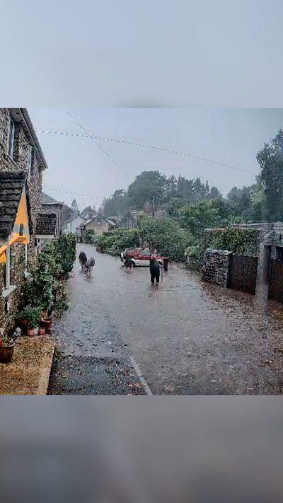 People standing in flash flooding in a village.