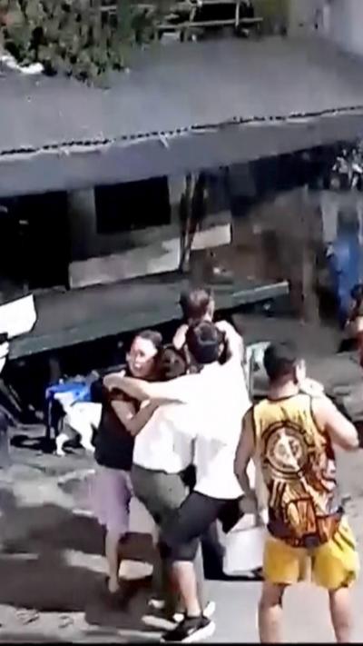People cling to each other in a street.