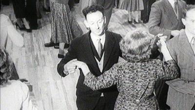 Couples dance in a hall.