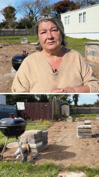 Woman with grey hair in front of a caravan, a barbecue next to a pile of breeze blocks