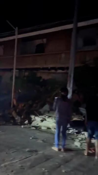 A person looks on at a pile of rubble next to a wall