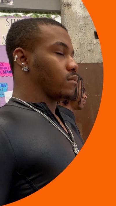 A teenager wearing a black top, mindfully closes his eyes in a classroom
