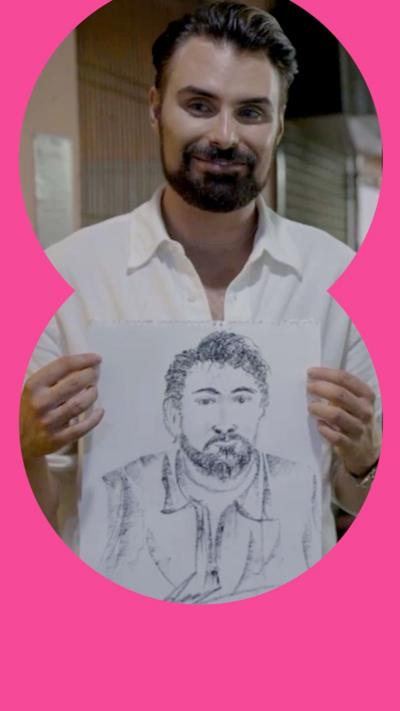 Rylan holds up a black and white portrait of himself on a piece of white paper