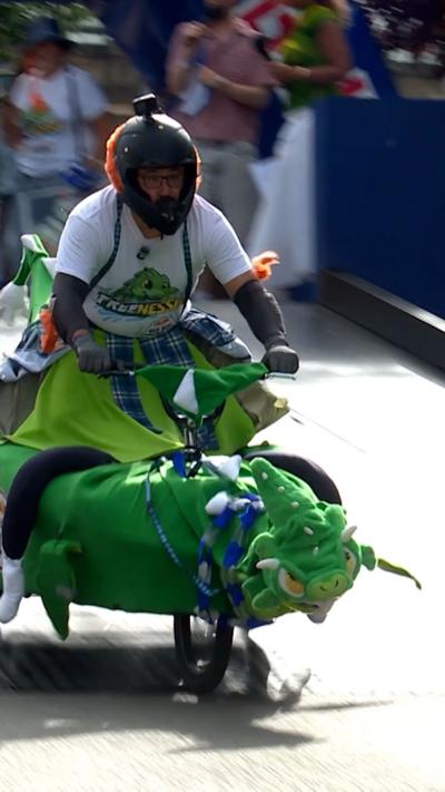 Man with helmet on cart decorated like green monster