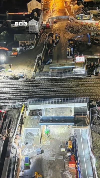 A bridge over a road with roadworks at night.