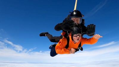 Lloyd sky diving through blue skies in a harness with an instructor