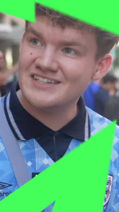 A young man in an England shirt being interviewed on the street.