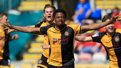 Bobby Kamwa with arms outstretched and other Newport players celebrate