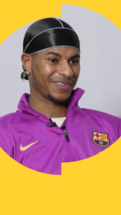 Marcus Rashford smiles during an interview. He wears a purple sports top with the FC Barcelona shield 