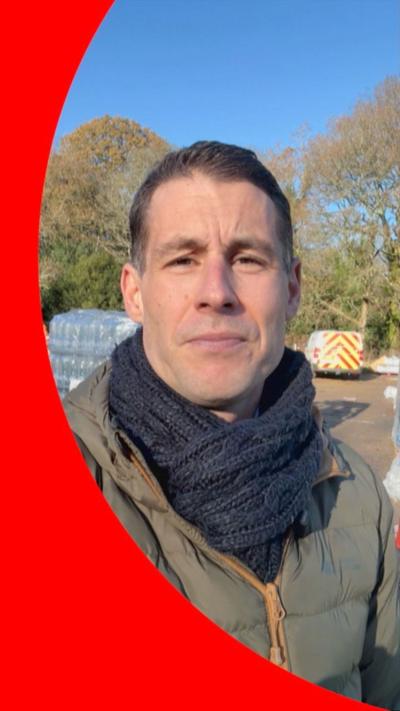 A man in a scarf in a carpark