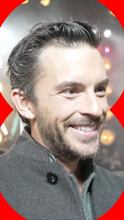 Jonathan Bailey smiles with bright lights in the background