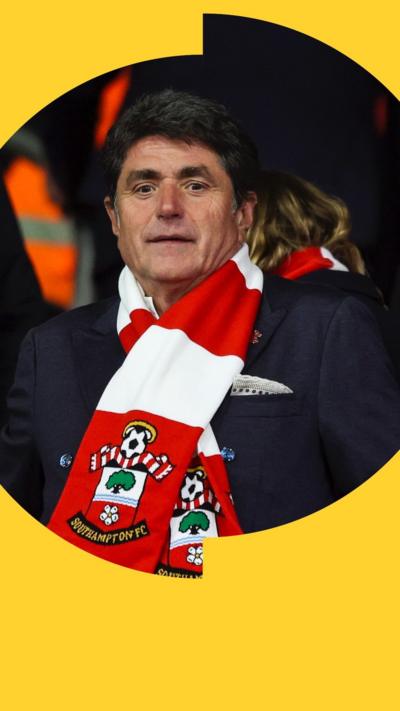 Southampton FC owner Dragan Solak looks straight ahead. He is wearing a red and white Southampton scarf.