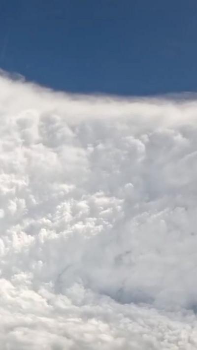 A cloud towers vertically into the sky, with blue sky visible at top