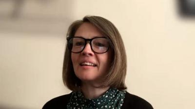 Eilidh NicFhionghain, na suidhe air beulaibh chamera agus gàire air a h-aodann