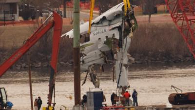 Crews use a crane to lift plane wreckage out of a river.