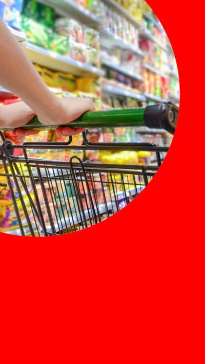 A shopping trolley being pushed in a supermarket. Hands visible