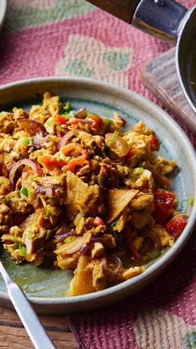 A blue plate with a curry on top, sits on a red and green tablecloth.