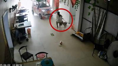 A girl grabs a toddler as a car smashes through a restaurant window 