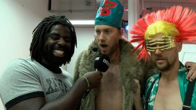 Kofi with two performance artists wearing colourful outfits