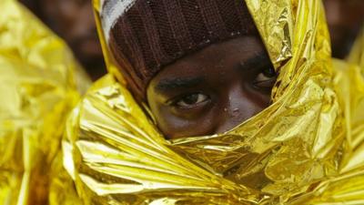 A migrant waits to disembark from a Coast Guard ship in the Sicilian harbour of Messina