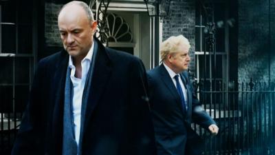 Dominic Cummings outside Downing Street with Prime Minister Boris Johnson behind him walking to the right.