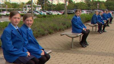 Six sets of twins sitting on benches