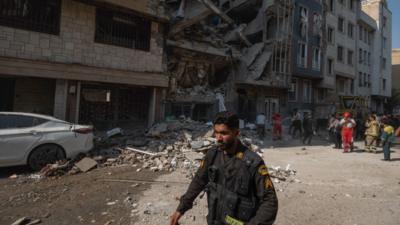 Iranian police officer walks past a damaged building in Tehran.