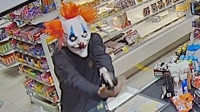 Man holding gun wearing clown mask