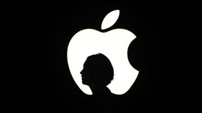 A woman silhouetted against the Apple logo