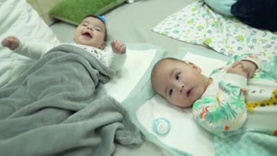 Two babies lying on a mat