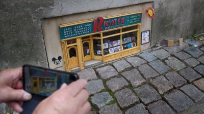 Person uses mobile phone to take a picture of a tiny music shop