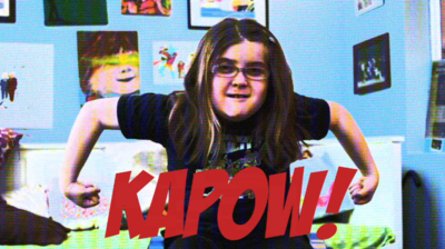 Emily White in superhero pose with KAPOW written across the middle