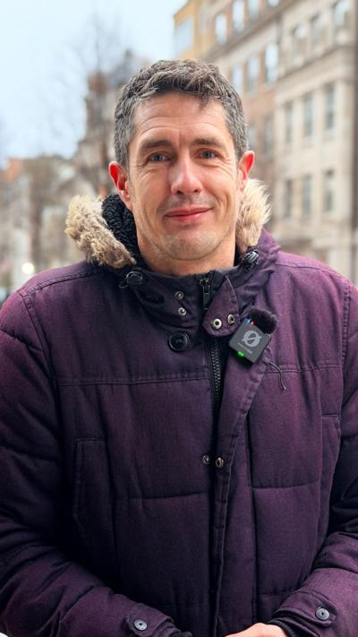 BBC Weather presenter Chris Fawkes wearing a purple winter coat
