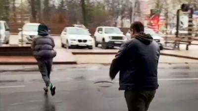 People run to their car in a street in Donetsk