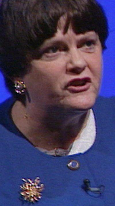 A woman with a blue jacket talking off camera. 