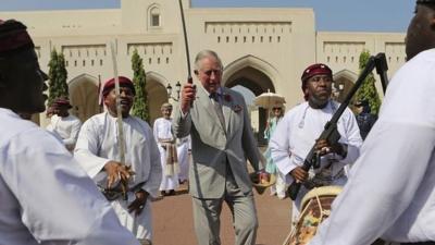 Prince Charles dances with a sword with a group of Omani traditional dancers in Muscat, Oman