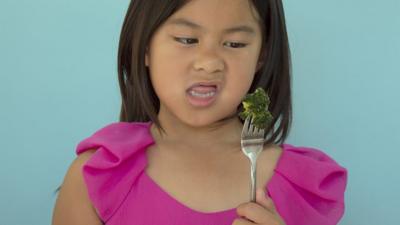 Child looking at a piece of broccoli