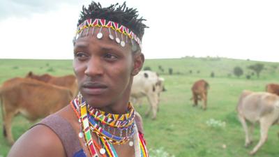 Richard Turere with his goats in the background