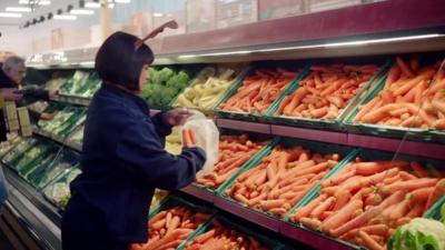 Women picking carrots at a supermarket