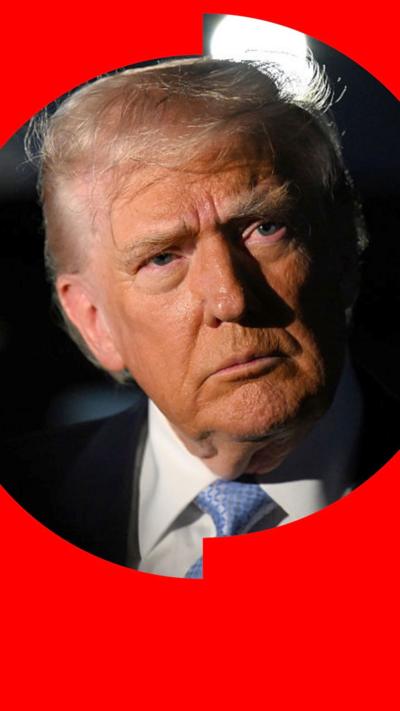 Donald Trump with a solemn expressions looks to the side of the camera