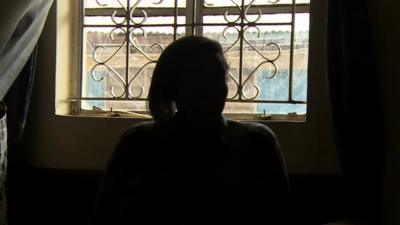 Woman in Kenya silhouetted against window