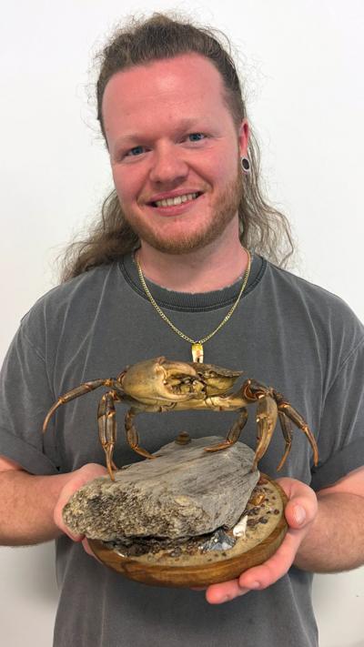 Jason Philip - man with long hair, smiling, holding a crab taxidermy on a plinth