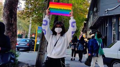 Person holding Pride flag on a street in Iran