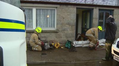 Firefighters place sandbags by residential properties