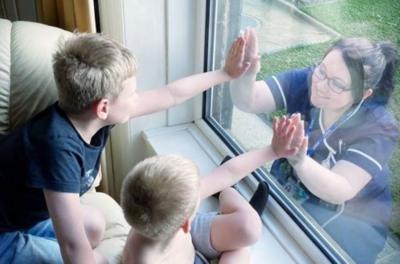 Care nurse touches palms with children separated by window