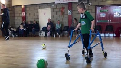 A boy uses a frame to play football